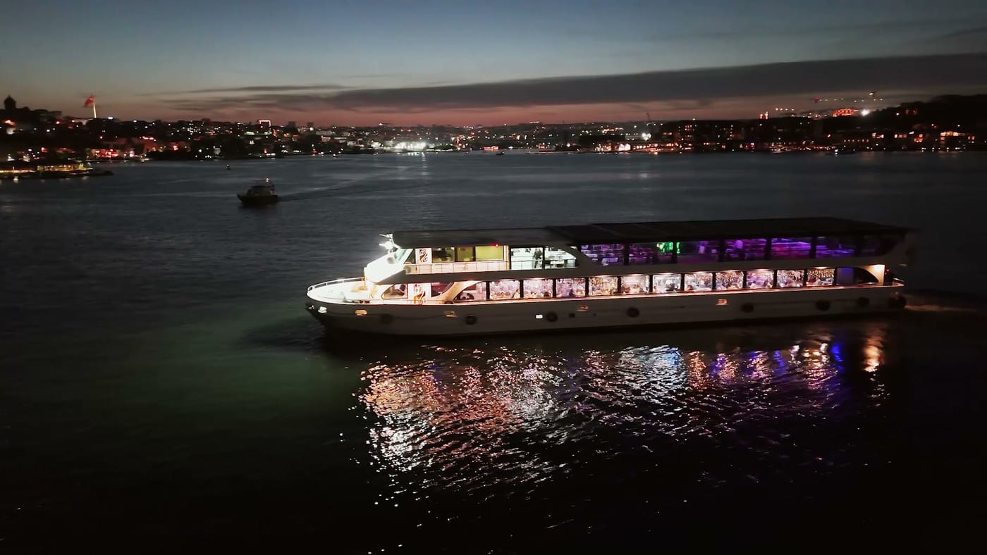 The boat lit up on the strait at dusk