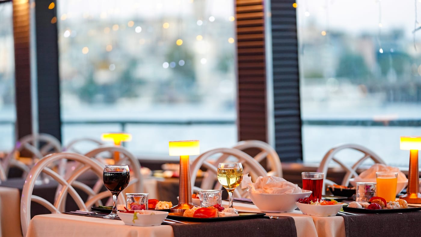 Window tables at twilight, lamps lit, the city beyond the glass