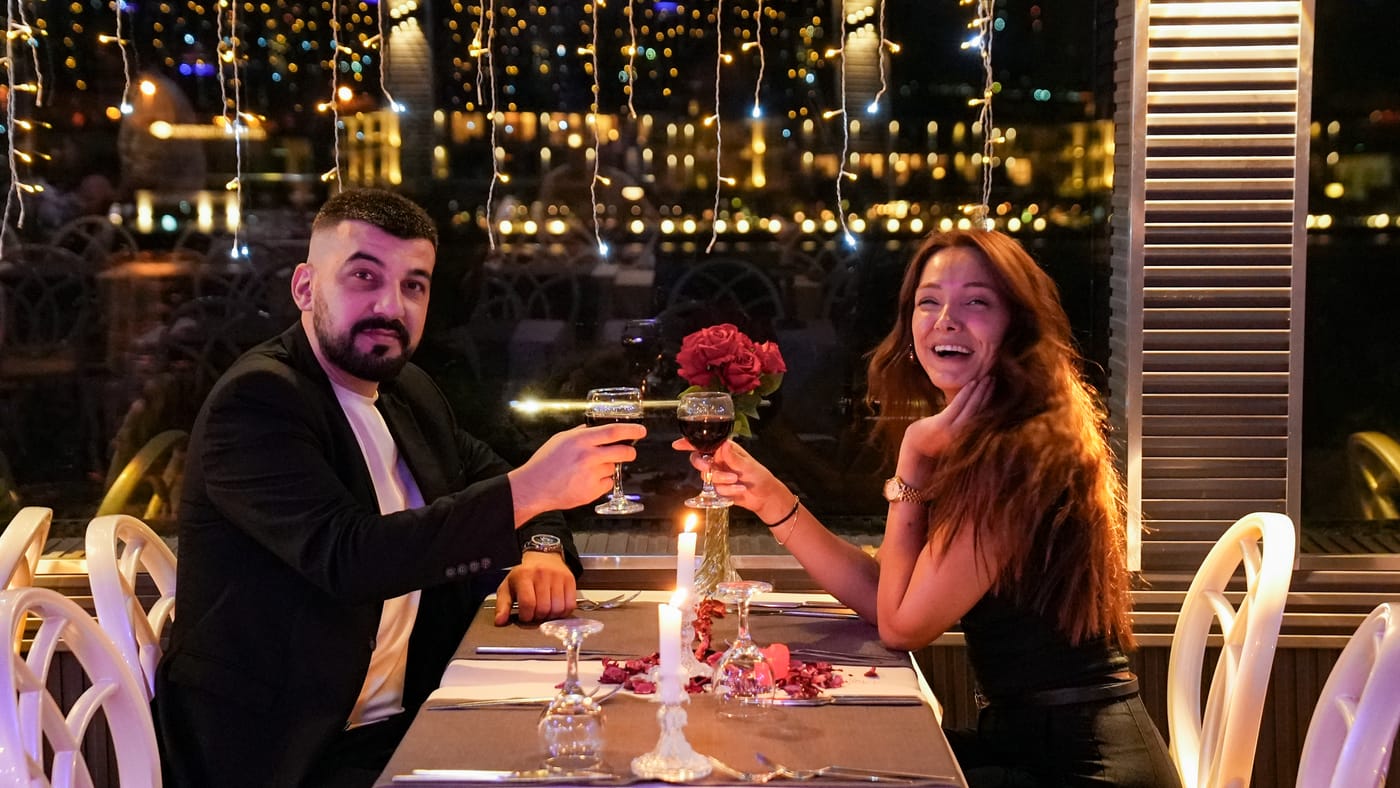 Two guests raise their glasses at a window table