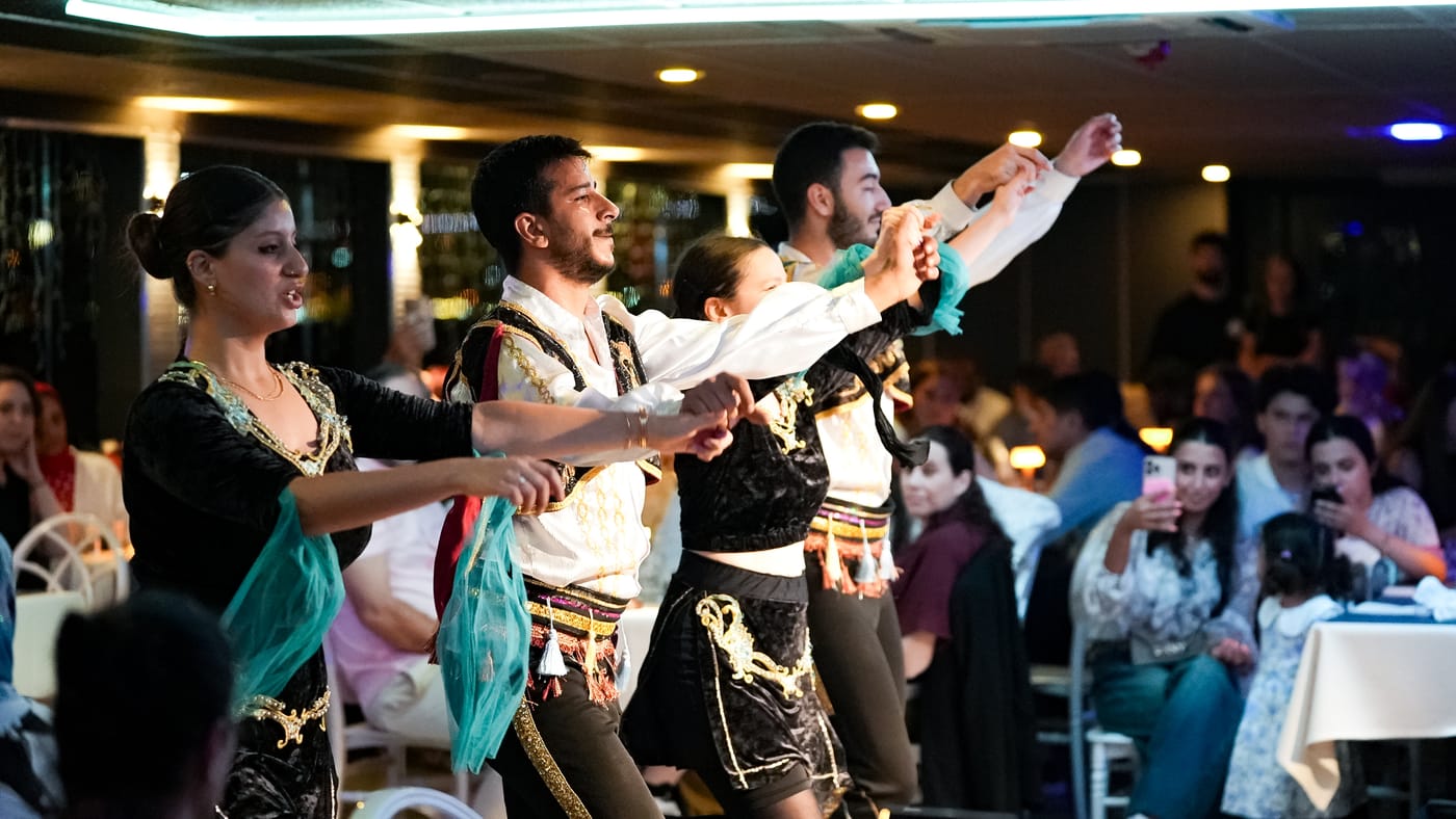 Folk dancers link hands along the tables