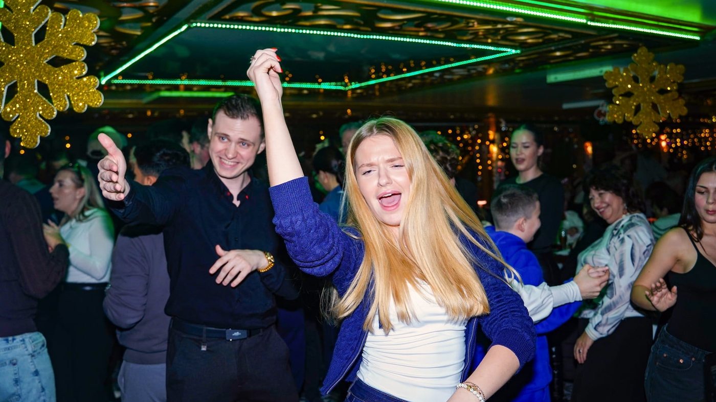Guests dancing in the salon under festive gold decorations and lights