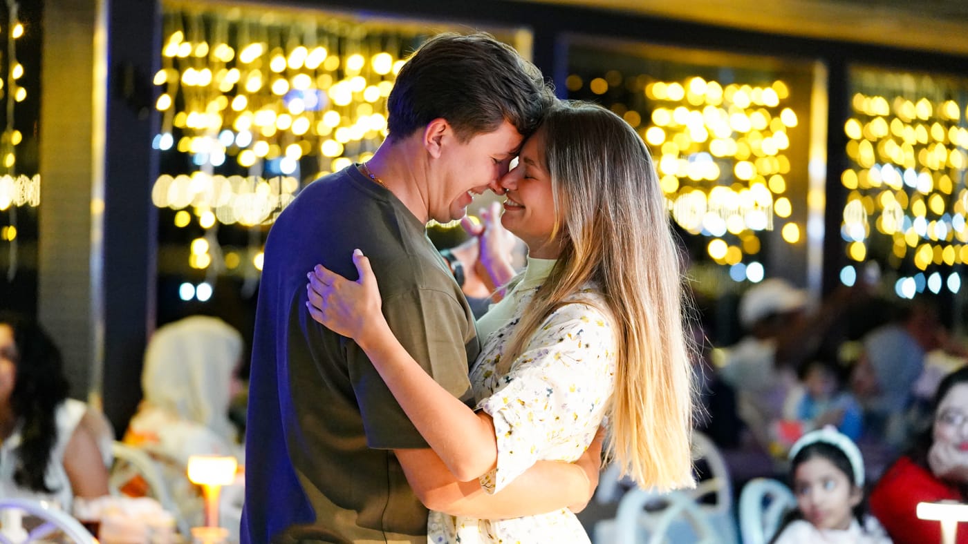 Eyes closed, a couple dance close together