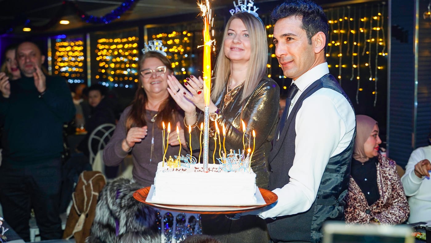 A cake with candles and a sparkler arrives at the table